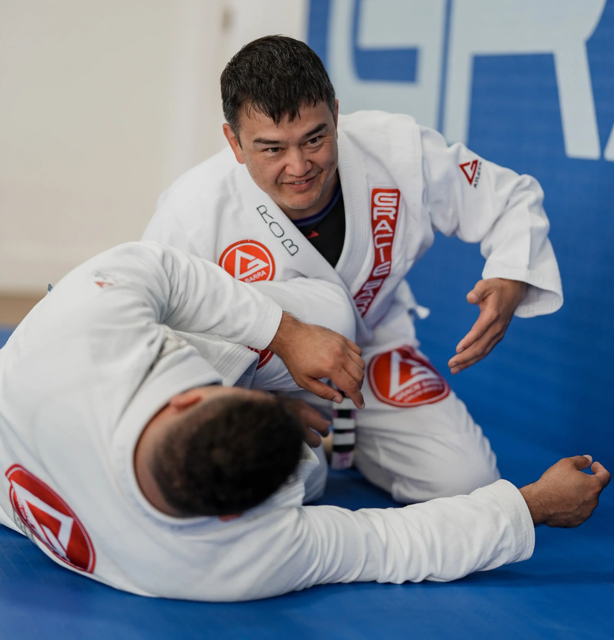 Adult Jiu-Jitsu Training Partners Adults training BJJ techniques together during an evening class at Gracie Barra San Marcos